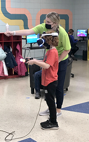 Program leader helping youth with video game.