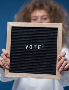 Image of woman holding a sign with text "vote"